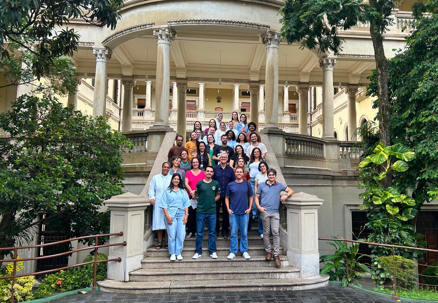 Descrição da imagem: foto de um grupo de educadores perfilados numa escadaria do colégio Santa Marcelina.