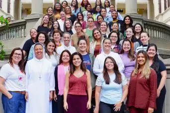 Descrição da imagem: foto de um grupo de 50 educadoras perfiladas num lance de escadas e sorrindo.